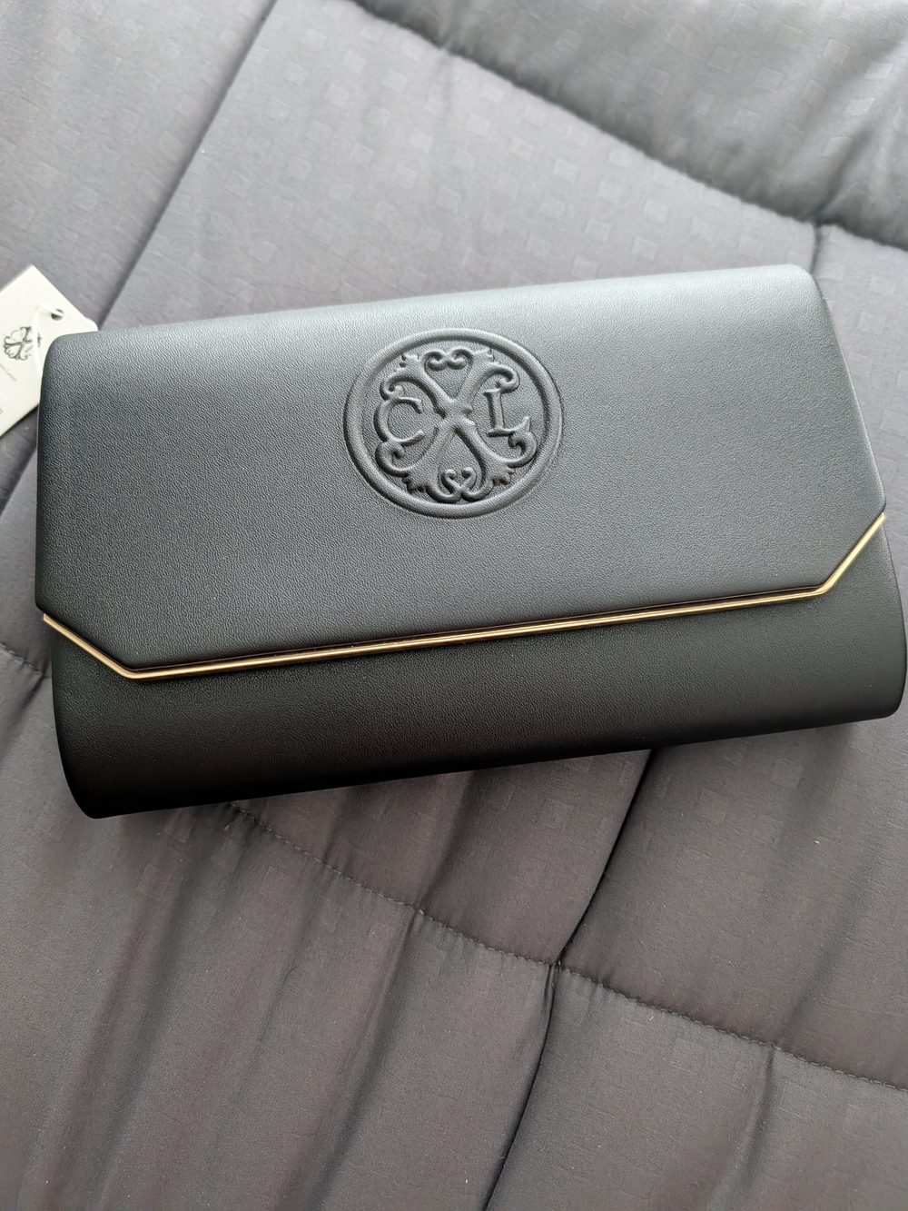 The Sak Black Clutch with Gold Trim and Embossed Logo